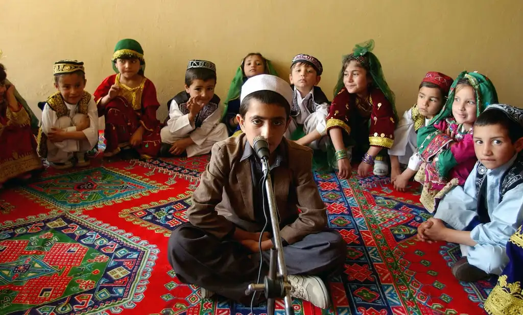 a young afghani boy leads a song performed by students at the asheiy school