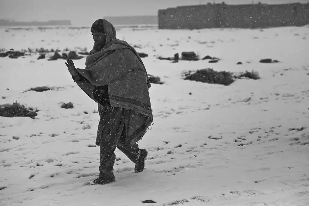 an afghan man waves as he walks in the snow around